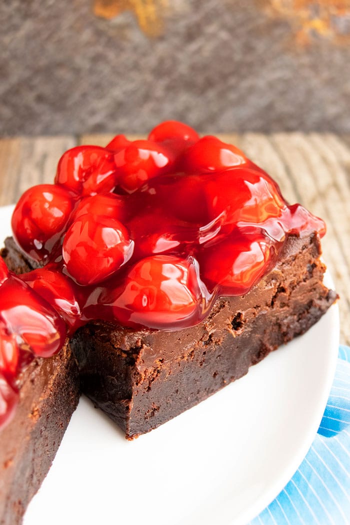 Easy Homemade Gooey Chocolate Brownies With Chocolate Frosting and Cherry Pie Filling on White Plate