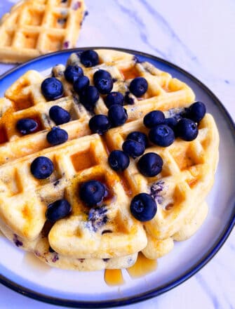 Stack of Easy Homemade Blueberry Waffles on White Plate with Light Blue Background