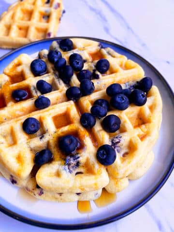 Stack of Easy Homemade Blueberry Waffles on White Plate with Light Blue Background