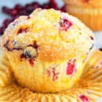 Quick, Soft, Fluffy, Easy Cranberry Orange Muffins on White Background With Liner Partially Removed.