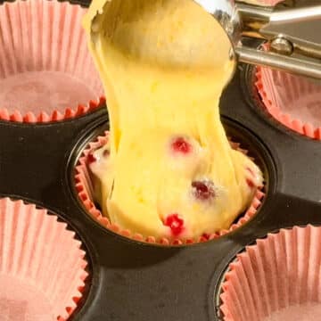 Batter being poured into liners in a muffin pan. 
