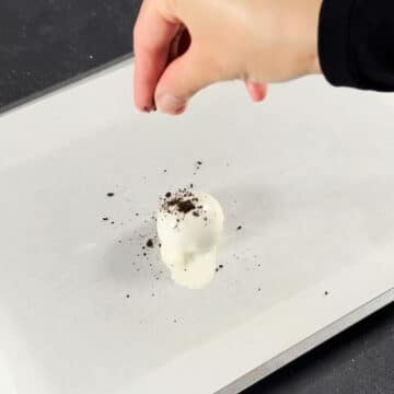Crushed Oreos being tossed on top of ball. 