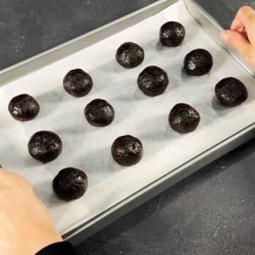 Cookie balls placed on a tray lined with parchment paper. 