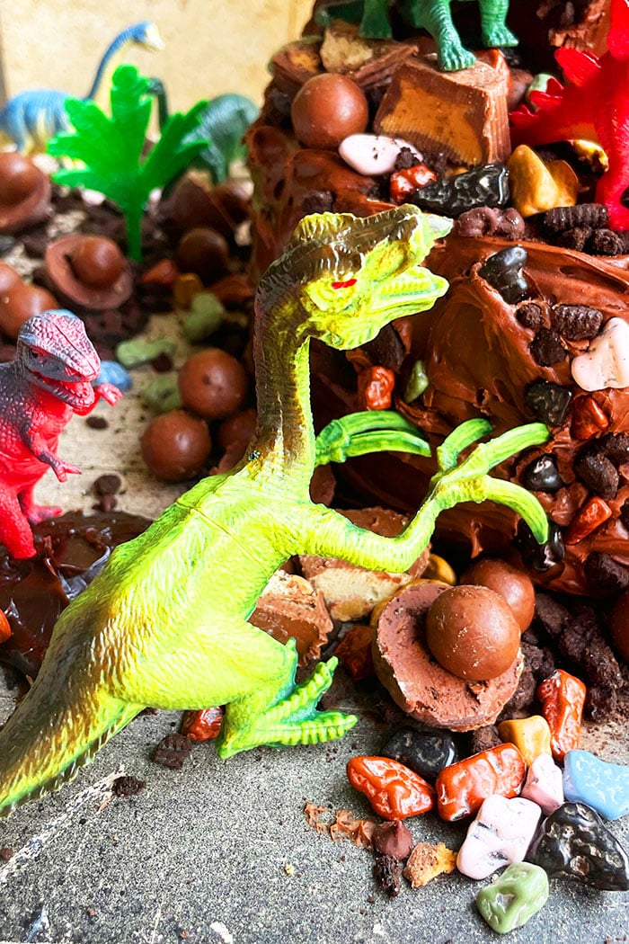Jurassic World Cake or Jurassic Park Cake- Closeup Shot of Green Dinosaur Toy Climbing on Side of Birthday Cake