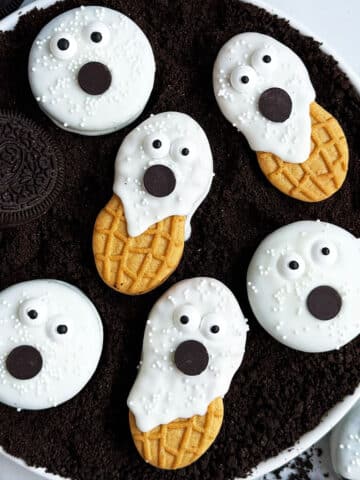 Easy Ghost Cookies With Oreos and Nutter Butter on White Dish With Cookie Crumbs.