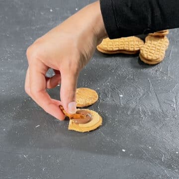Melted chocolate and pretzel rod being added to cookie. 