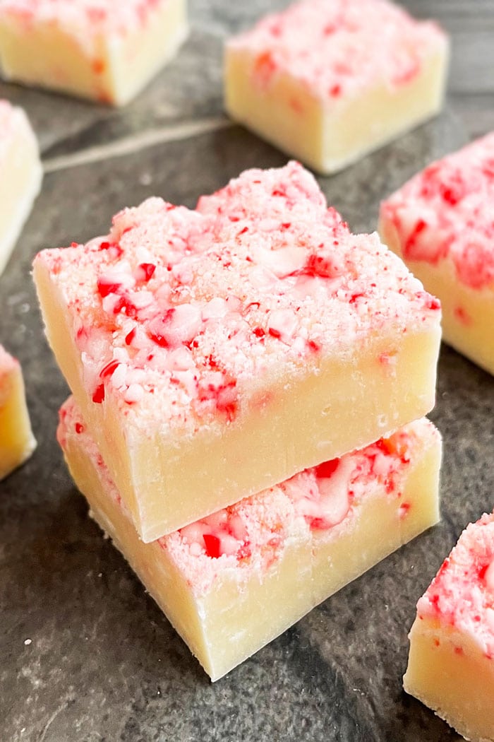 Stack of Easy Christmas Fudge With Peppermint Candy Canes on Gray Background