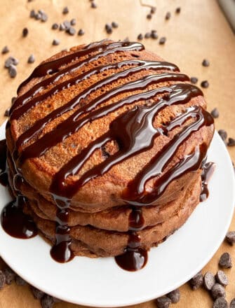 Easy Fluffy Chocolate Pancakes With Hot Fudge Sauce Stacked on White Dish