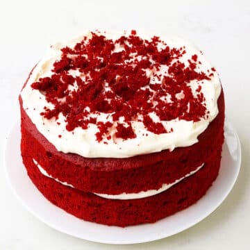 Best easy soft and moist red velvet cake (layer cake) with cream cheese frosting on white dish and white background.