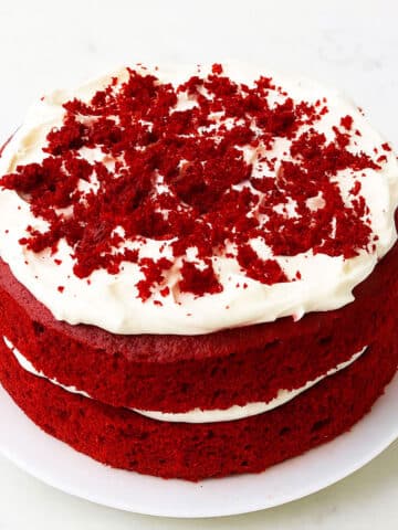 Best easy soft and moist red velvet cake (layer cake) with cream cheese frosting on white dish and white background.