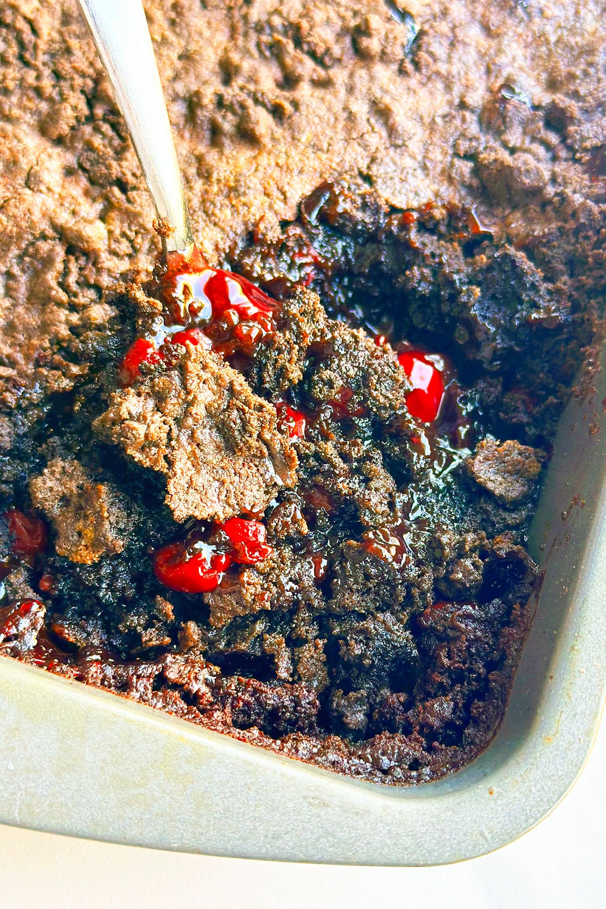 Spoonful of Cherry Dump Cake in Baking Pan- Closeup Shot