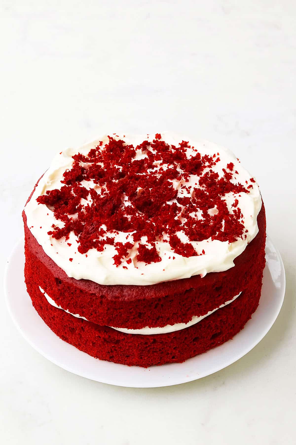 Best easy soft and moist red velvet cake (layer cake) with cream cheese frosting on white dish. 