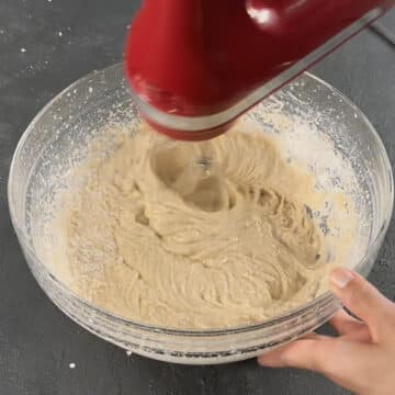 Cake batter being mixed with hand-held mixer. 