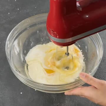 Eggs, buttermilk and oil being mixed in a glass bowl. 