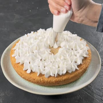 Buttercream frosting being piped on top of cake. 