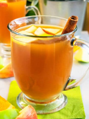 Easy Homemade Slow Cooker Apple Cider in Glass Cup on Green Napkin.
