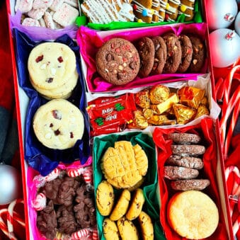 Easy Homemade Christmas Cookie Boxes on a Red Holiday Background With Ornaments.