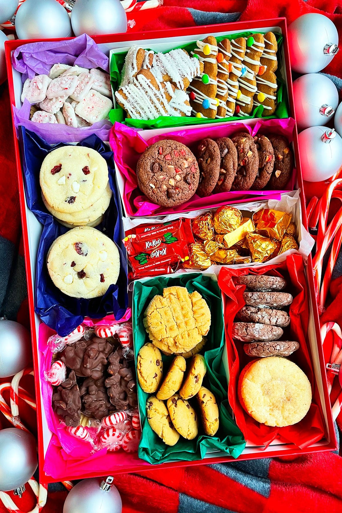 Easy Homemade Christmas Cookie Boxes on a Red Holiday Background With Ornaments.