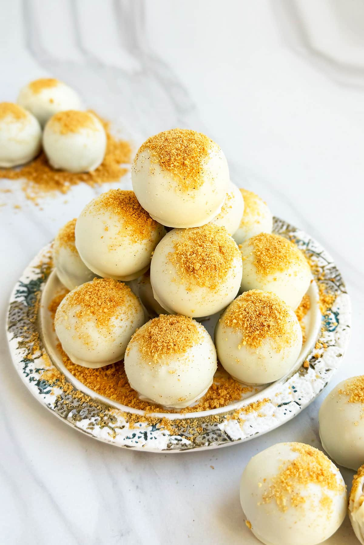 Stack of easy homemade pumpkin truffles balls coated in white chocolate on dish with marble background. 