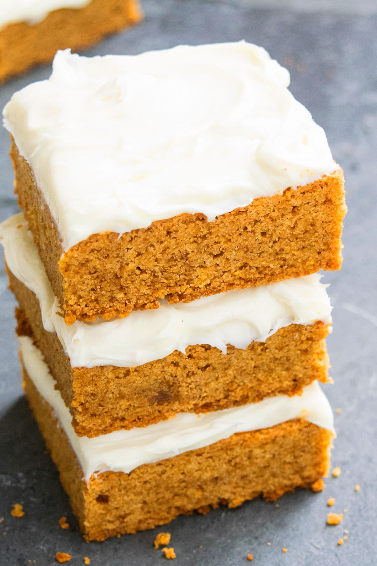 Stack of Easy Pumpkin Bars With Cream Cheese Frosting on Rustic Gray Background.