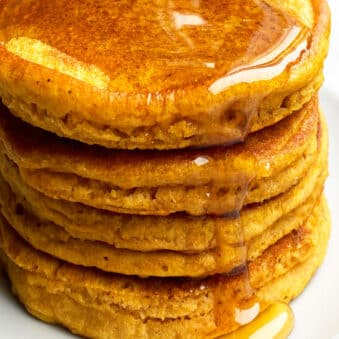 Stack of Easy Pumpkin Pancakes With Maple Syrup on White Dish.
