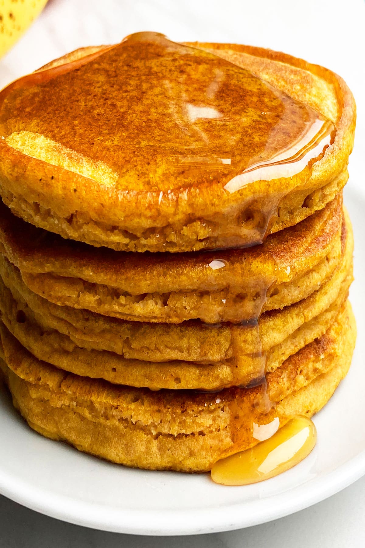 Easy Pumpkin Pancakes with Pumpkin Puree 6 Stack of Easy Pumpkin Pancakes With Maple Syrup on White Dish.