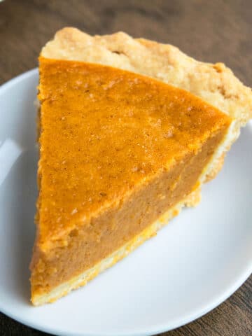 Easy Pumpkin Pie With Flaky Butter Pie Crust on White Dish.