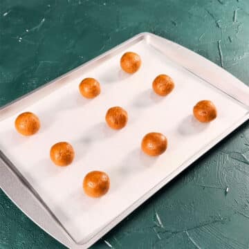 Cheesecake balls on a tray lined with wax paper. 