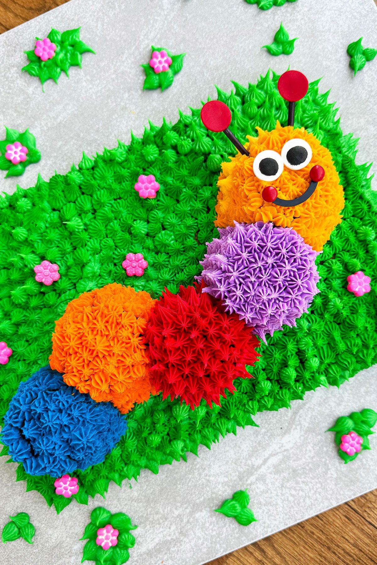 Easy Caterpillar Cake With Buttercream Icing on Light Gray Cake Board. 