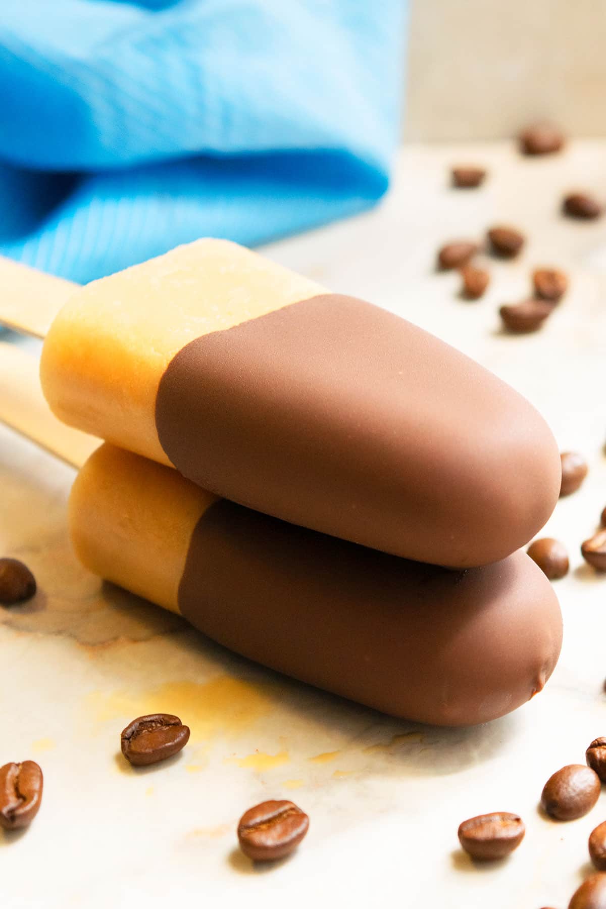 Stack of Chocolate Dipped Mocha Popsicles on Marble Background. 