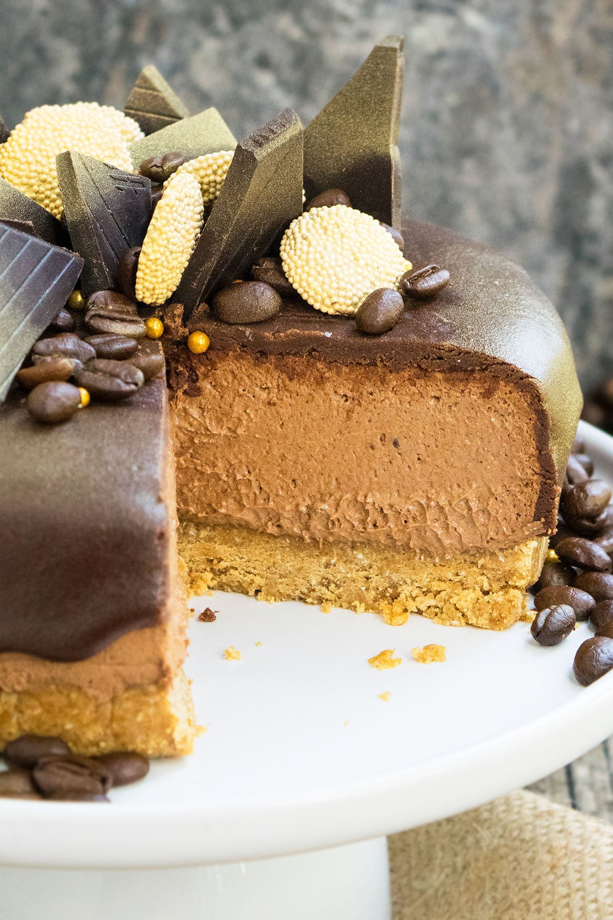 Easy No Bake Mocha Cheesecake With One Slice Removed on White Cake Stand. 