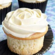 Easy Almond Cupcakes With Almond Buttercream Frosting on Blue Pattern Background- Liner Removed.