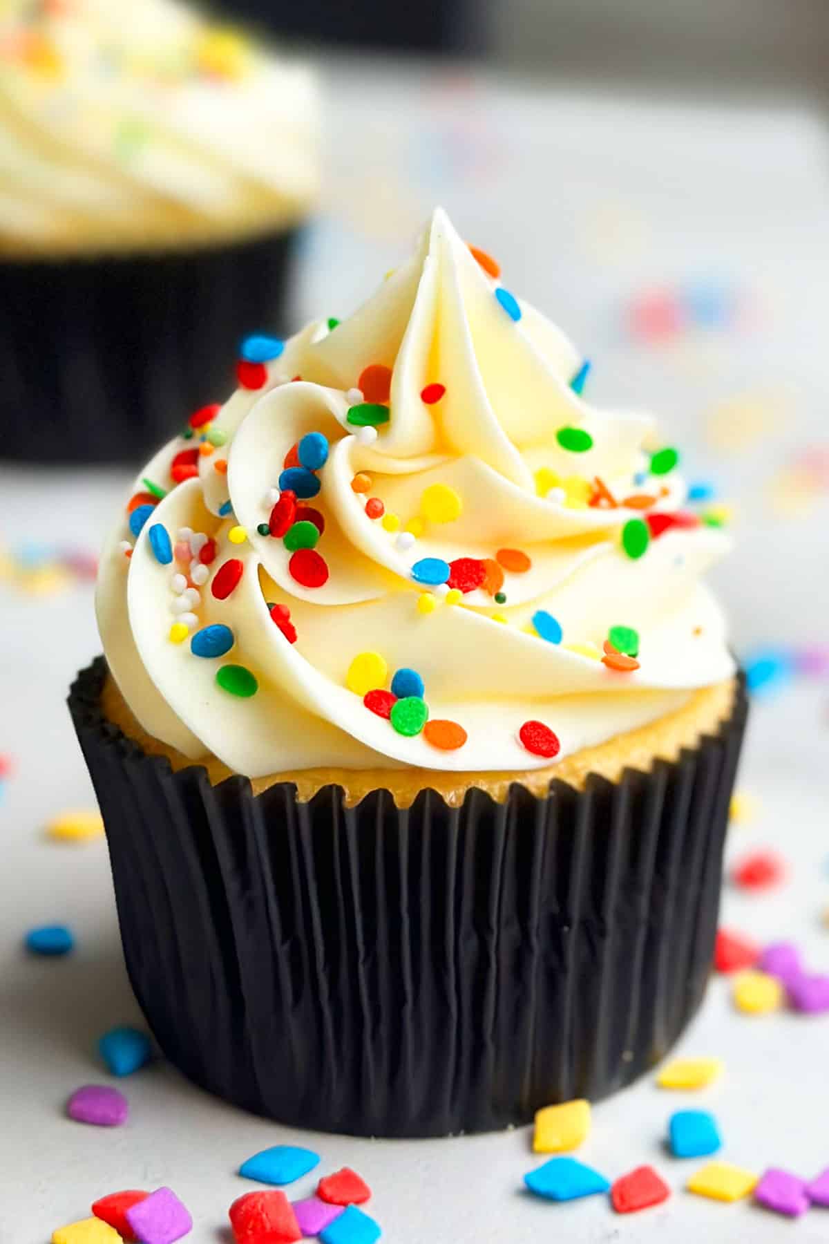 Easy Confetti Cupcakes With Rainbow Sprinkles in Black Liner on Marble Background. 