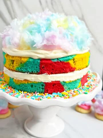 Easy Cotton Candy Cake With Whipped Cream Frosting on White Cake Stand.
