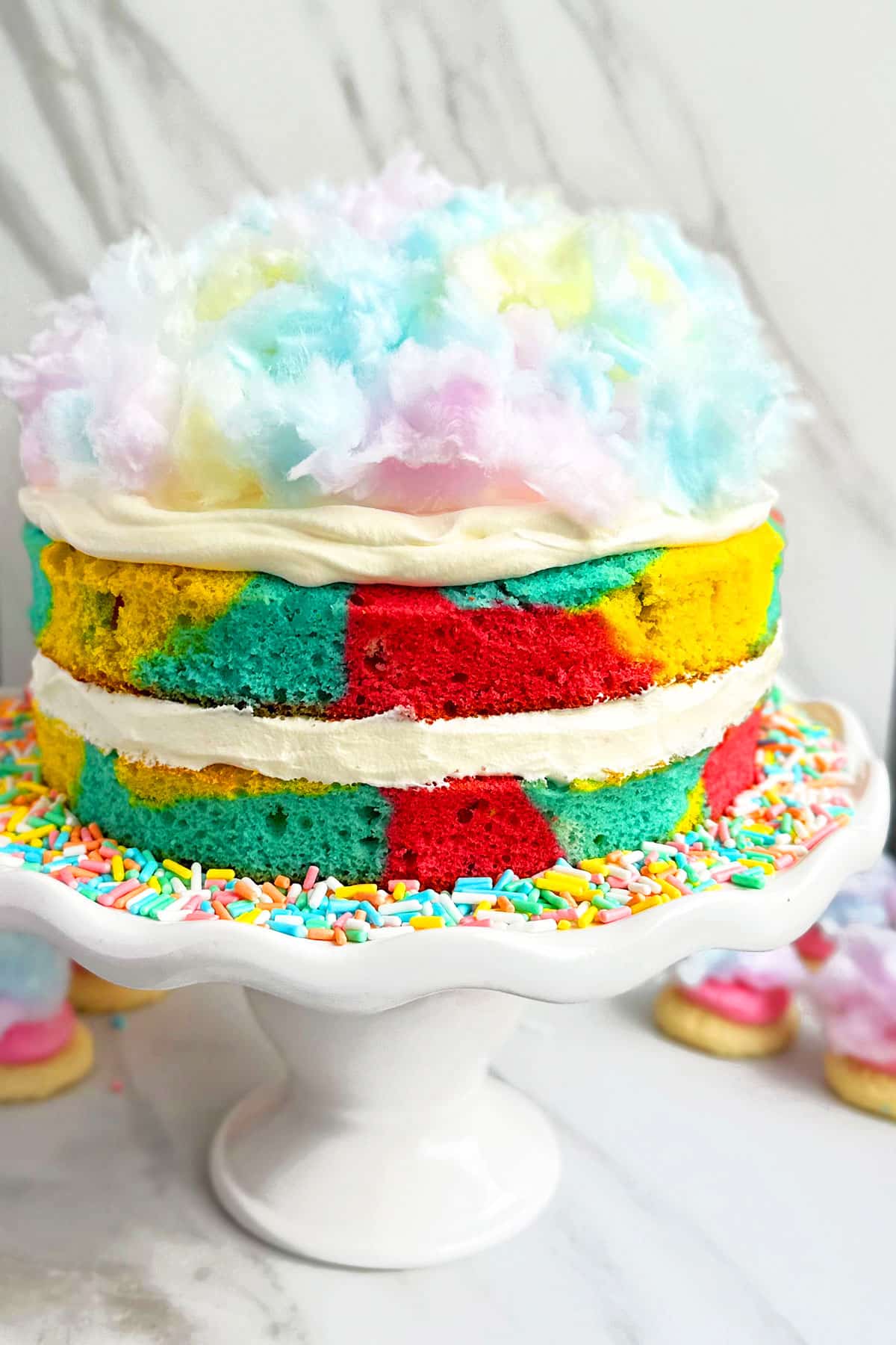 Easy Cotton Candy Cake With Whipped Cream Frosting on White Cake Stand.