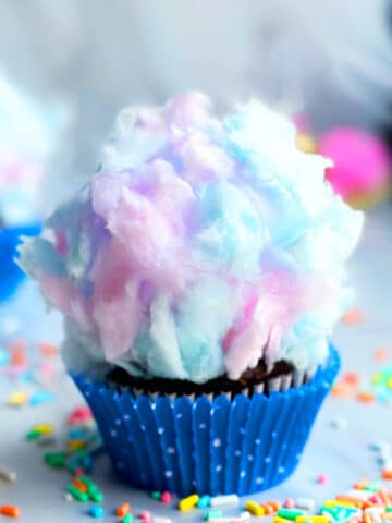 Easy Cotton Candy Cupcakes in Polka Dot Blue Liner on a Marble Background.