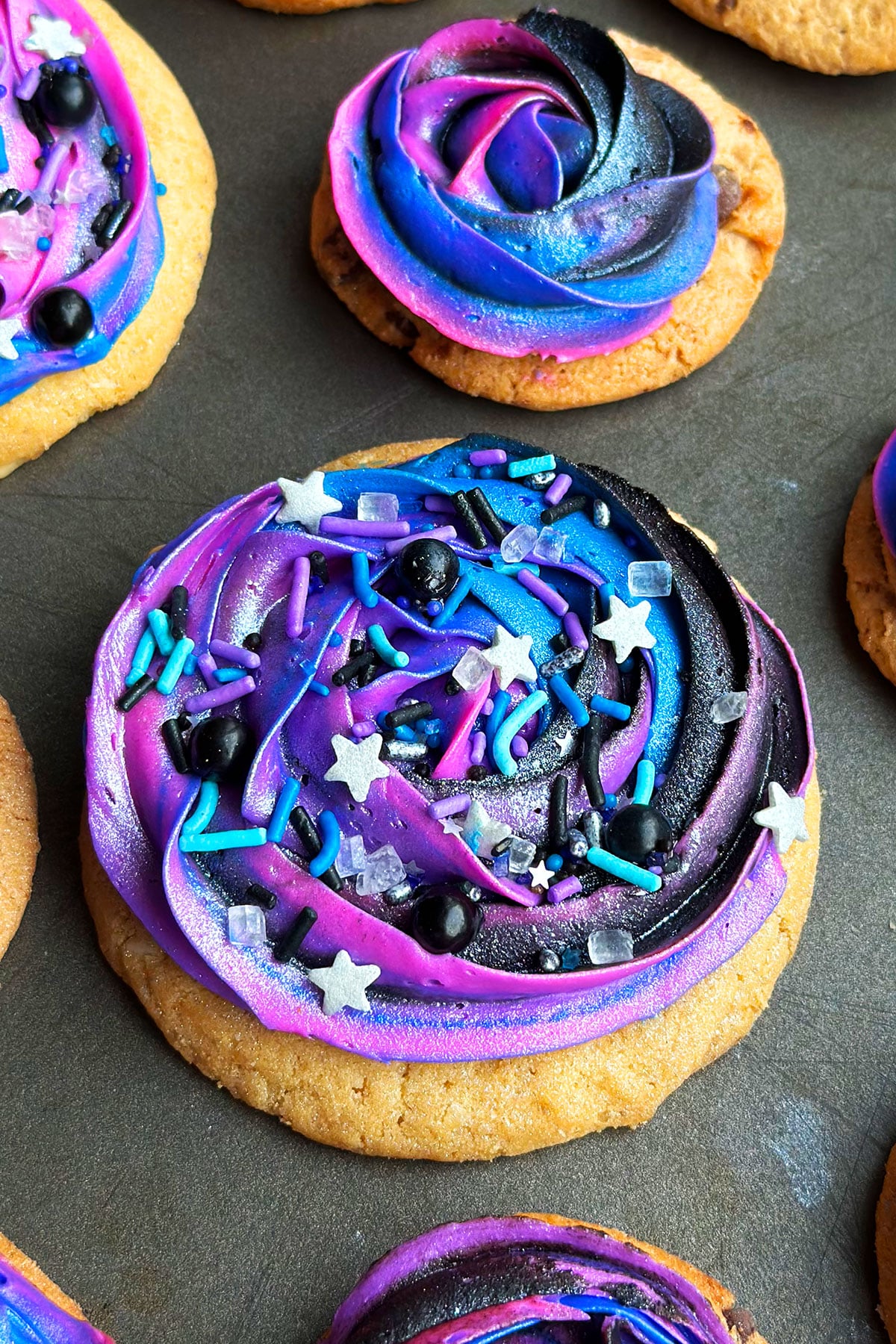 Easy Galaxy Cookies With Buttercream Icing and Sprinkles on Metallic Gray Tray. 