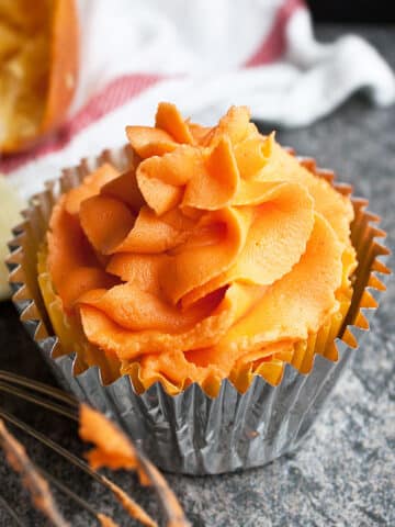 Easy Orange Frosting (Buttercream Icing) on Top of Cupcake on Rustic Gray Background.