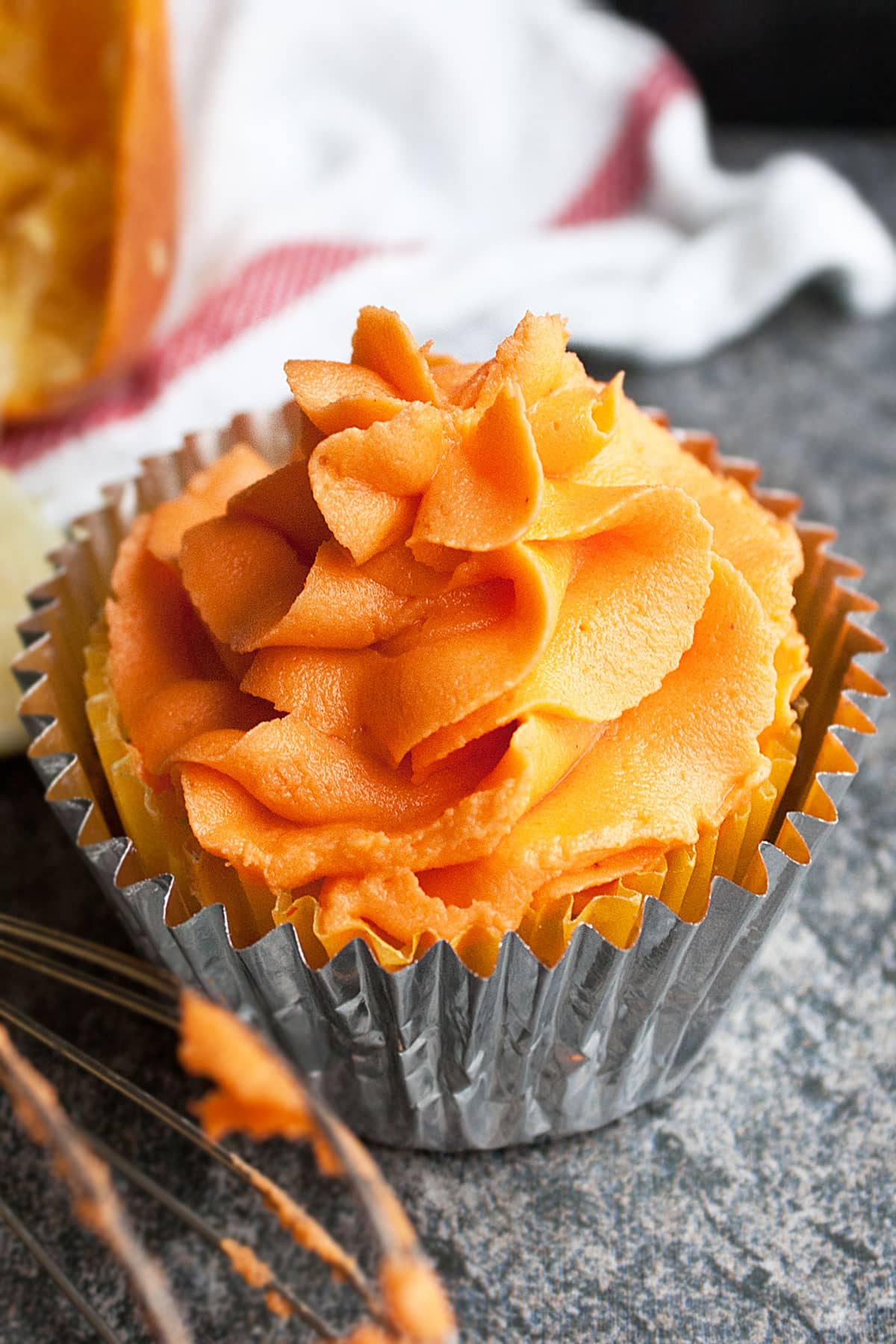 Easy Orange Frosting (Buttercream Icing) on Top of Cupcake on Rustic Gray Background.
