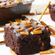 Slice of Easy Fudgy Chocolate Cake Mix Brownies With Ganache and Pretzels on White Napkin.