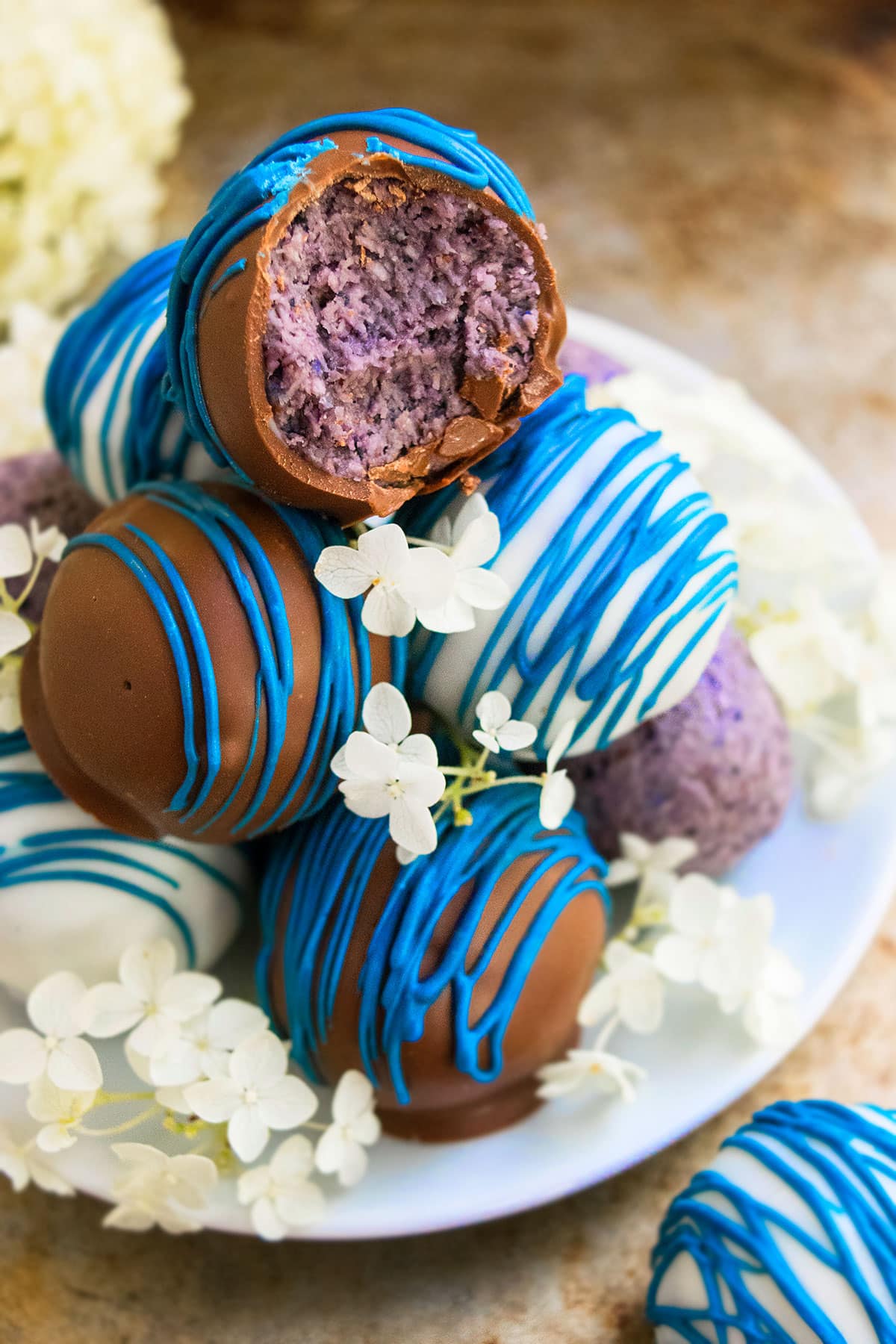 Stack of Chocolate Dipped Truffles on White Dish With Flowers. 