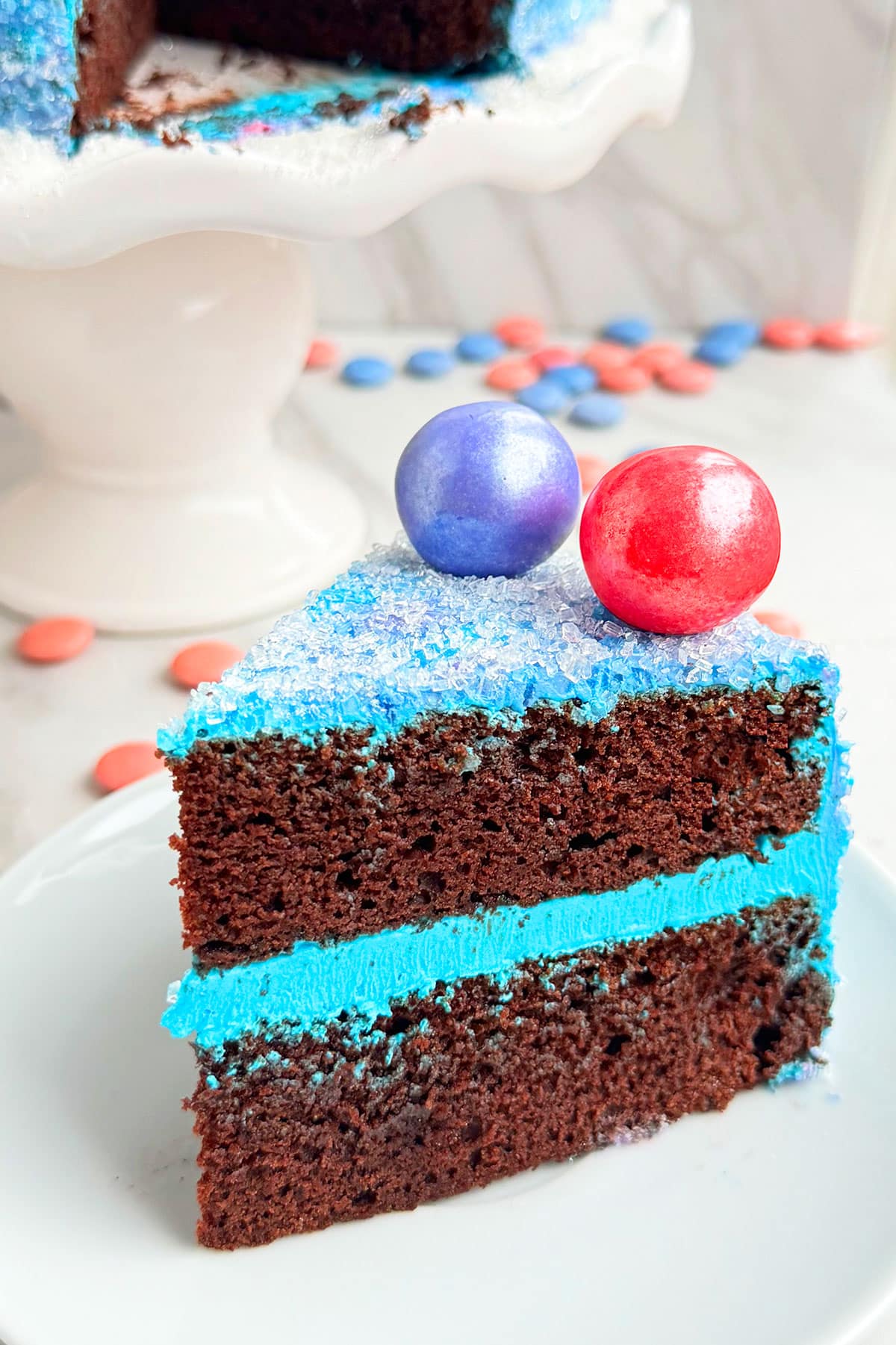 Slice of Chocolate Cake With Blue Buttercream Icing on White Dish. 