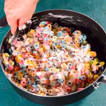 Cereal being mixed with melted marshmallow mixture in nonstick pot.
