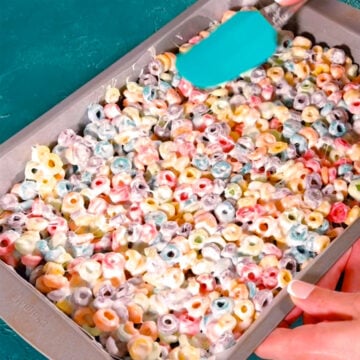 Sticky mixture being spread evenly with a spatula in rectangle pan. 