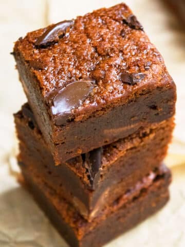 Stack of Fudgy Black Bean Brownies on Brown Parchment Paper.
