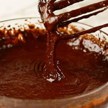 Smooth brownie batter dripping from whisk. 