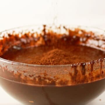 Cocoa powder added to batter in glass bowl. 