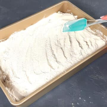 Cake mix powder being spread out evenly with a spatula. 