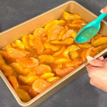 Apple pie filling being spread in a rectangle baking pan. 