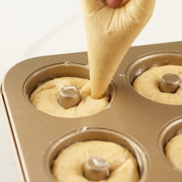 Donut batter being piped into donut pan. 